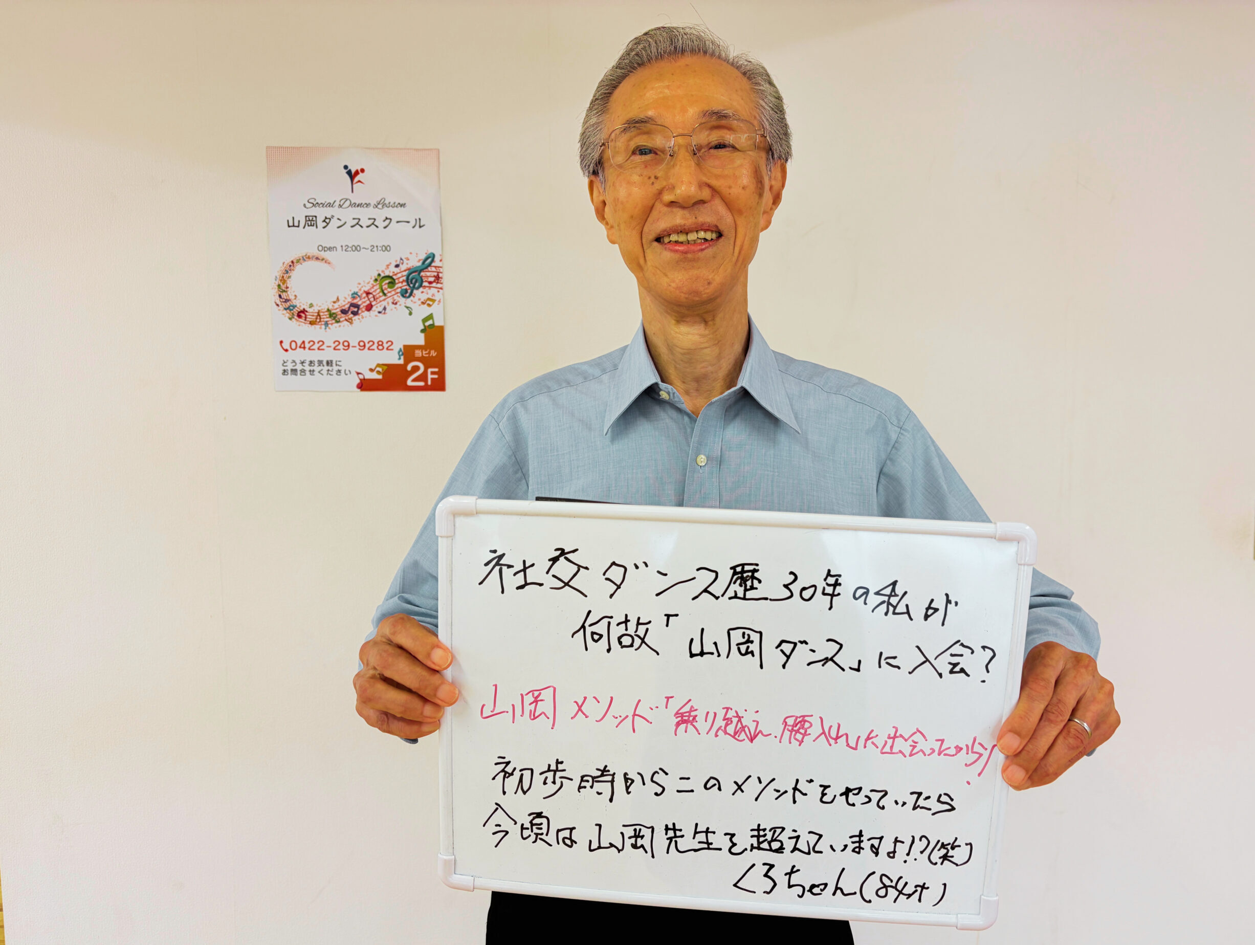 吉祥寺で社交ダンスを続ける84歳のKさんが生徒さんの声を書いたホワイトボードを持つ写真